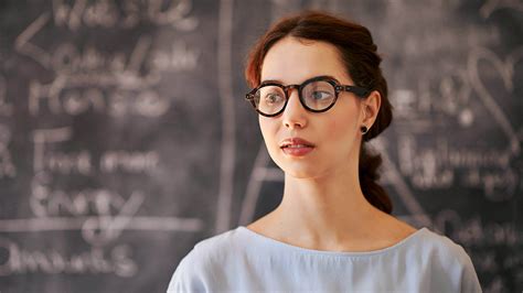 A Close Up Of A Female Teacher Wearing Glasses Looking Intently At Something French Classroom