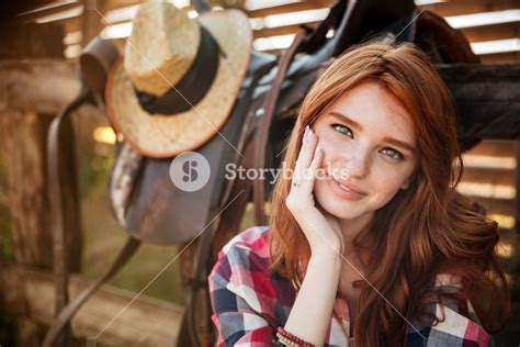 Close Up Portrait Of A Happy Beautiful Redhead Cowgirl Resting At The Ranch Fence Royalty Free