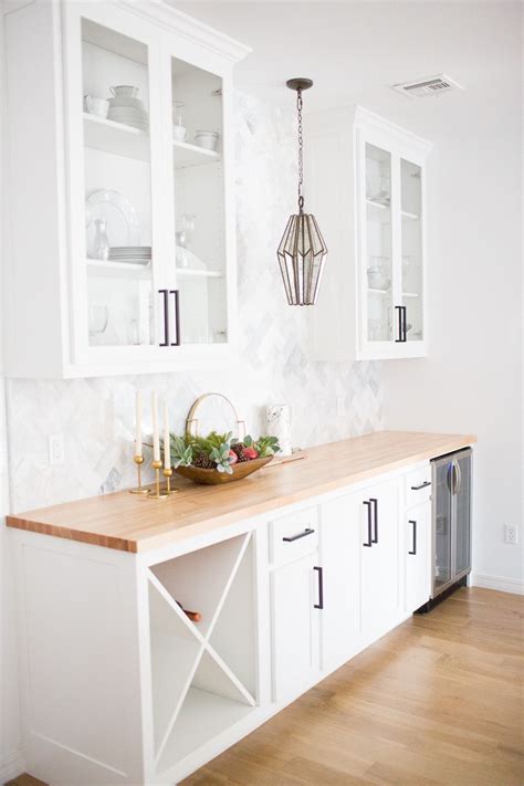 Contemporary setting for a white and green kitchen surrounded by cabinets made out of solid wood with a white coat of paint and dark handles and knobs. Modern White Farmhouse with Black Windows and Doors ...