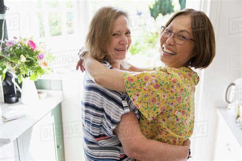 Portrait Affectionate Senior Lesbian Couple Hugging In Kitchen Stock Photo Dissolve
