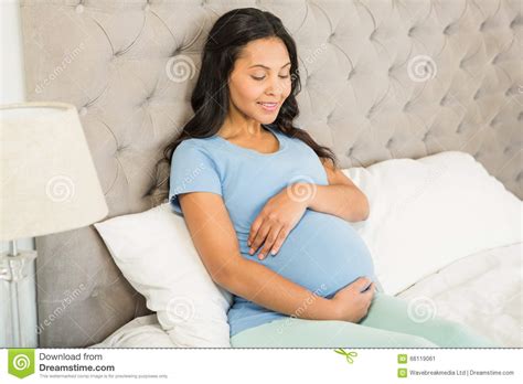 smiling pregnant brunette sitting on bed stock image image of leisure brunette 66119061