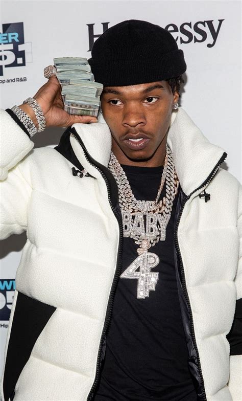 A Young Man In A White Jacket And Black Hat Holding Up A Stack Of Money