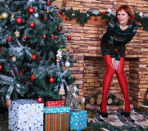 beautiful long legged redhead girl in red stockings and heels posing in christmas decoration