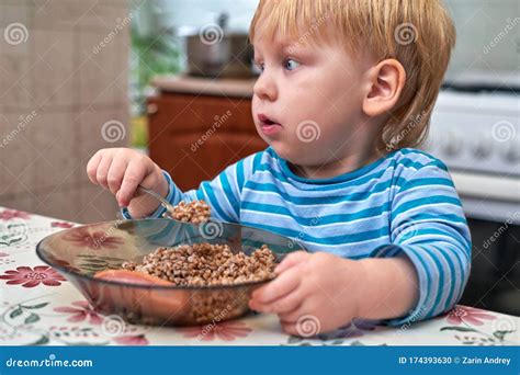 Blonde Babe Eats With A Spoon From The Porridge Plates In The Kitchen