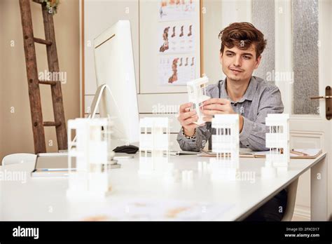 Male Architect Examining Architectural Model While Sitting At Table