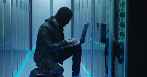 Hacker In Black Mask Using Computer And Breaking Servers Of Data Center