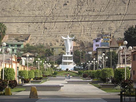 A Statue In The Middle Of A Park With Mountains In The Background