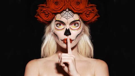 beautiful halloween make up style blond model wear sugar skull makeup with red roses santa