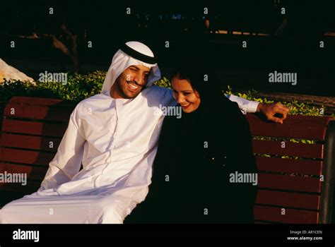 An Arab Couple Enjoying Themselves As They Are Seated On The Bench