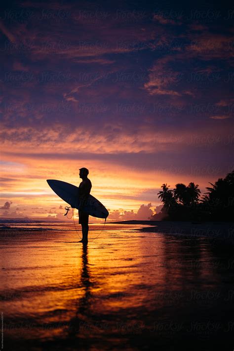 Silhouette Of A Surfer On The Beach With A Colorful Sunset By Stocksy