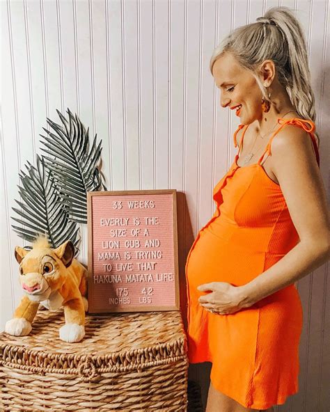A Pregnant Woman In An Orange Dress Standing Next To A Basket With A