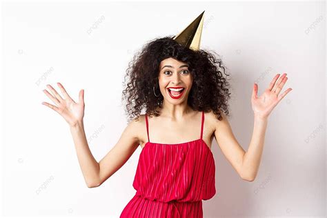 امرأة سعيدة في فستان أحمر تحتفل بعيد ميلادها بقبعة وابتسامة صورة الخلفية والصورة للتنزيل المجاني