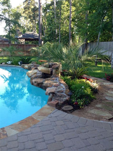 Beautiful Poolscaping Rock Waterfall In Front Of Lush Plants Landscaping Around Pool