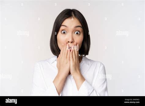 Close Up Face Of Asian Woman Gasping Looking Shocked And Speechless Holding Hands Near Mouth