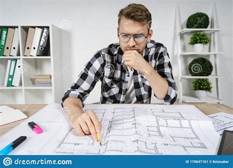 Young Adult Architect And Designer Working With Blueprints In Workspace