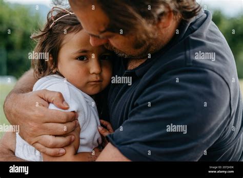 Father Embracing Daughter While Sitting At Backyard Stock Photo Alamy