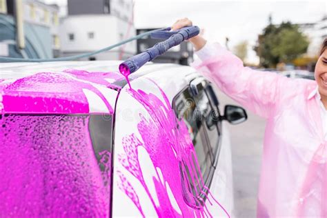 Caucasian Beautiful Woman Washing Car At Self Serve Car Wash With Pink