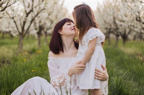 Madre cariñosa besando y abrazando a su hija en el jardín Foto Premium