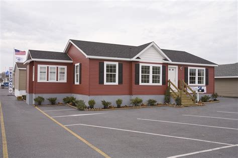 A Red House With White Trim And Black Shutters In A Parking Lot Next To
