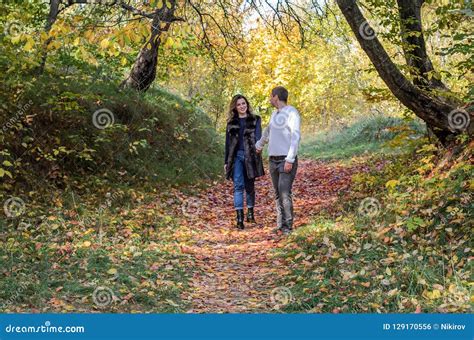 Young Couple In Love Walking In The Autumn Forest Among The Yellow