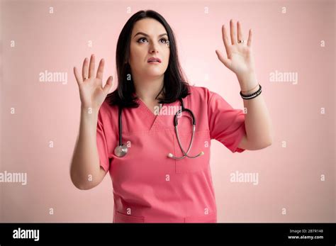 Portrait Of Beautiful Woman Doctor With Stethoscope Wearing Pink Scrubs Showing Fear With Her