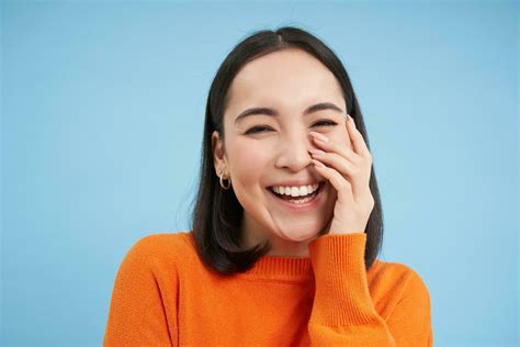 Happy Korean Woman Laughing And Smiling Expresses Candid Emotions Of Joy Standing Over Blue