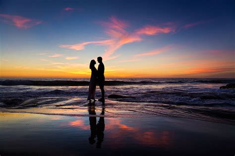 Epic romantic Silhouette photo of a couple on the reflecting beach at the pacific ocean right ...