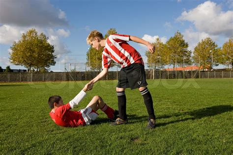 A Young Football Player Helping Another Player Stock Image Colourbox