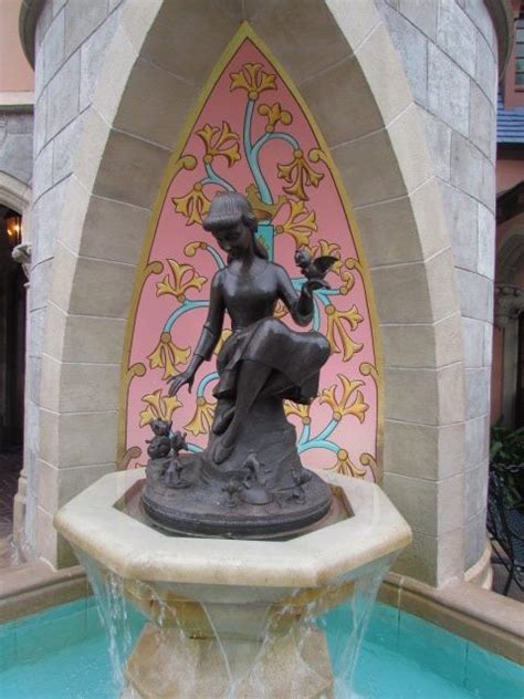 There Is A Fountain With A Statue On It In Front Of A Pink And Blue Wall