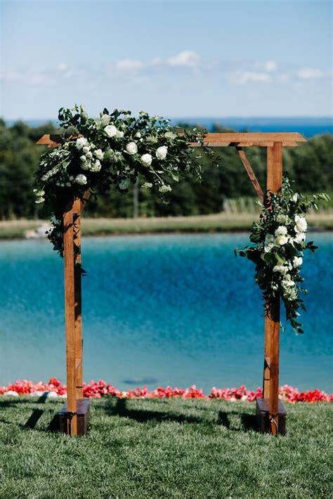 A Wooden Wedding Arbor Covered In A Large Corner Spray And A Smaller
