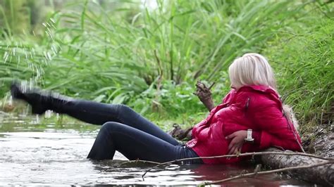 wetlook by girl in fully wet jacket tight jeans and shoes on lake