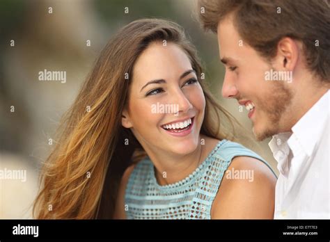 Funny Couple Laughing With A White Perfect Smile And Looking Each Other Outdoors With Unfocused