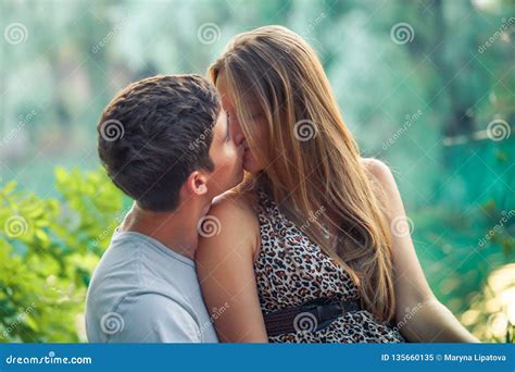Beautiful Young Couple On A Date In Nature Near The Lake In The Forest Hugging Kissing And