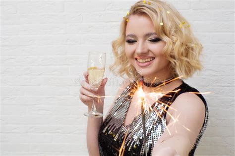 Happy And Cheerful Blonde With A Glass Of Champagne And A Sparkler In