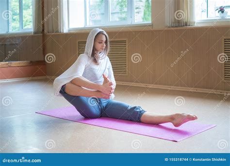Young Slim Woman With Blonde Hair Sitting On The Yoga Mat And