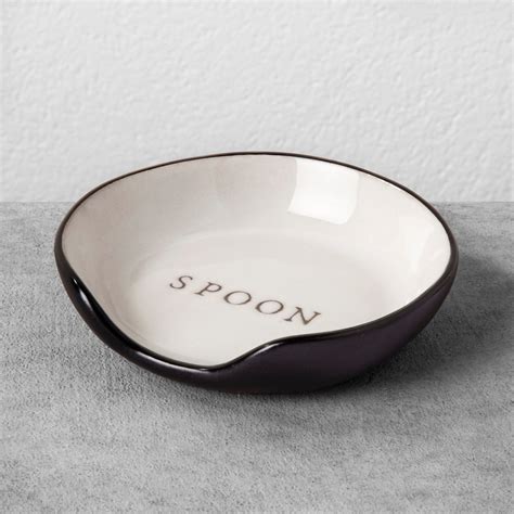 A Black And White Bowl Sitting On Top Of A Gray Tablecloth Next To A Wall