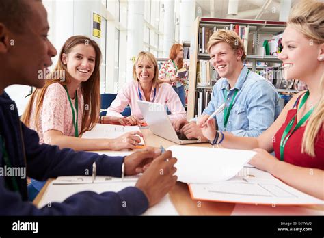 Group Of Students Working Together In Library With Teacher Stock Photo