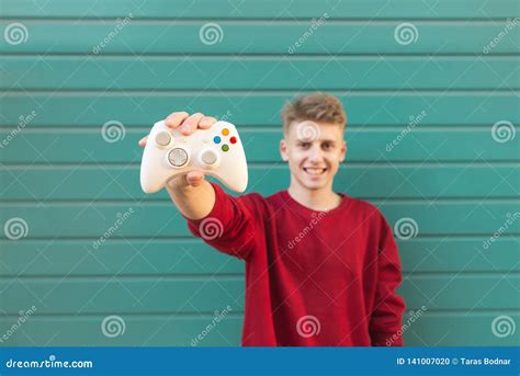 Smiling Young Gamer With A Gamepad In His Hand Against The Background