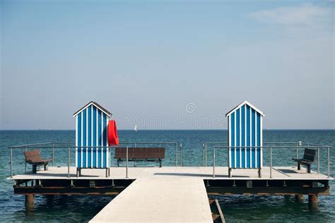 End Of Pier With Two Wooden Houses As Changing Room And Benches On Blue