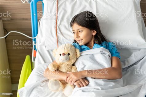 Hospitalized Sweet Girl Lying Down On Bed Looking Away While Hugging
