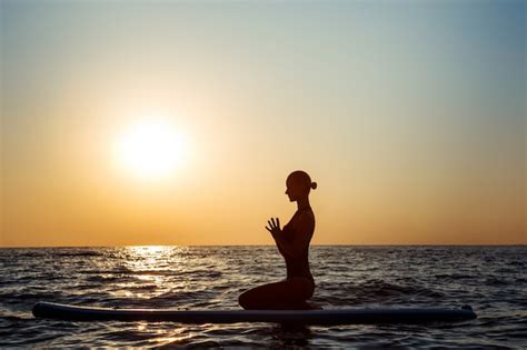 Schattenbild Der Schönen Frau Die Yoga Auf Surfbrett Bei Sonnenaufgang