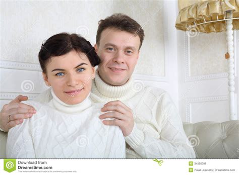 The businessman came home from work. Smiling Husband In White Sweaters Hugs Wife Shoulders ...