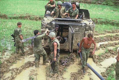 Men In Mud Suits And Helmets Are Working On An Army Vehicle That Is