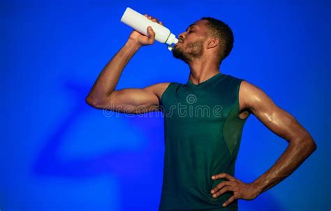 Black Sporty Guy Drinking Water After Exercising Over Blue Background