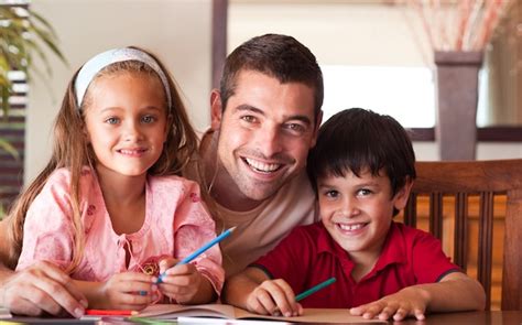 Padre Sonriente Que Ayuda A Sus Hijos Para La Tarea Foto Premium