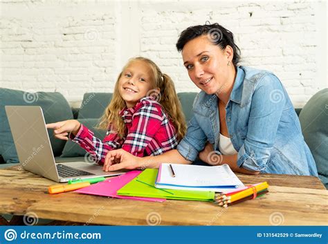 Mother Helping Young Girl Doing Homework With Laptop And ...