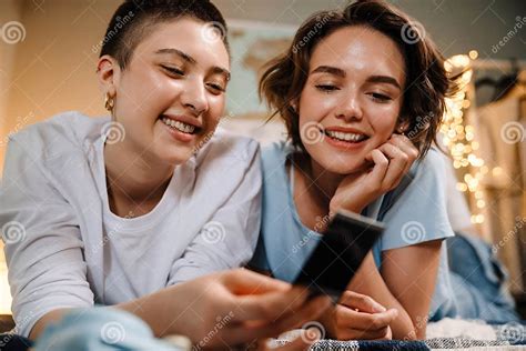 lesbian girls smiling and holding photo while lying in bed at home stock image image of people