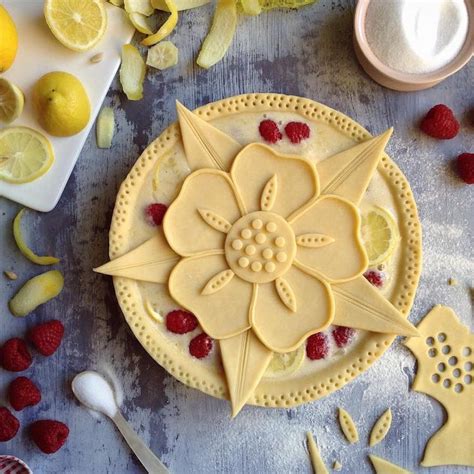 A Cake Decorated Like A Flower With Raspberries And Lemons Next To It
