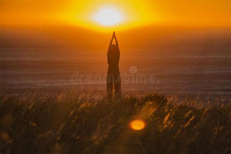 Silhouette Of A Beautiful Woman Standing And Praying At Sunset Or