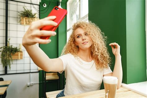 Premium Photo Beautiful Curly Blonde Woman Taking Selfie While Sitting At The Table In Coffee Shop